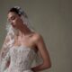 Close-up portrait of a model in a lace strapless wedding gown wearing a floral-edged veil.