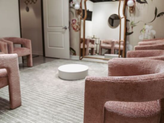 Cozy bridal fitting lounge with plush pink chairs, full-length mirrors, and a round white coffee table.