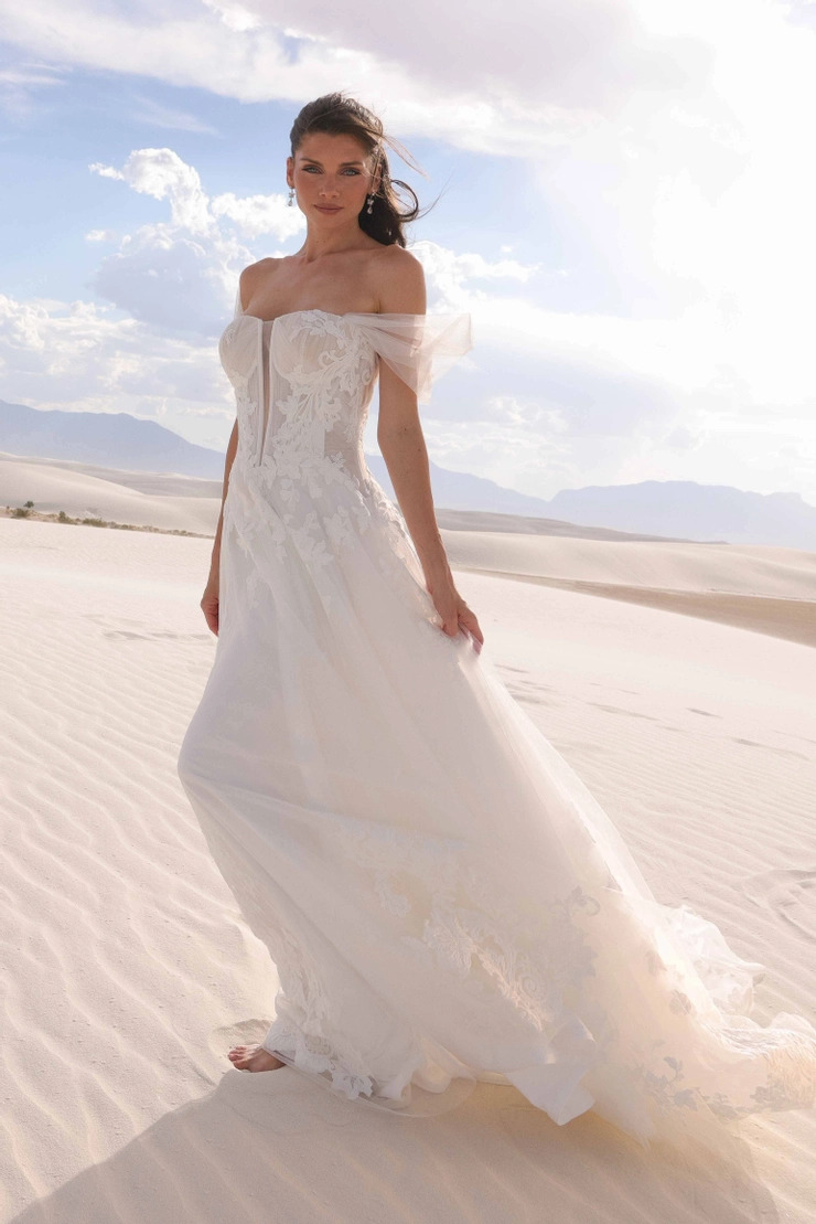 Bride wearing a flowing off-the-shoulder wedding gown while walking across white sand dunes.