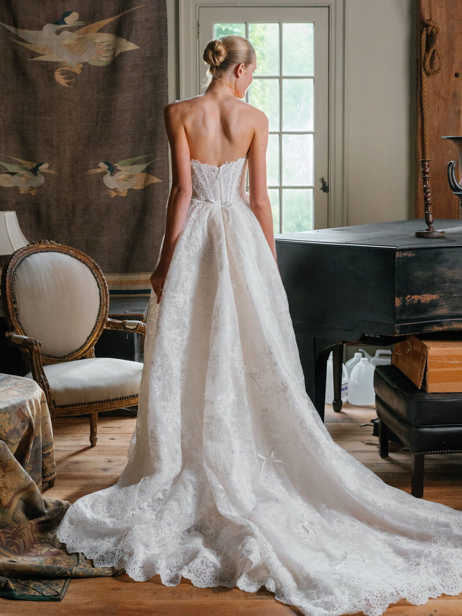 la premiere bride looking down at a grand piano wearing a strapless wedding gown.