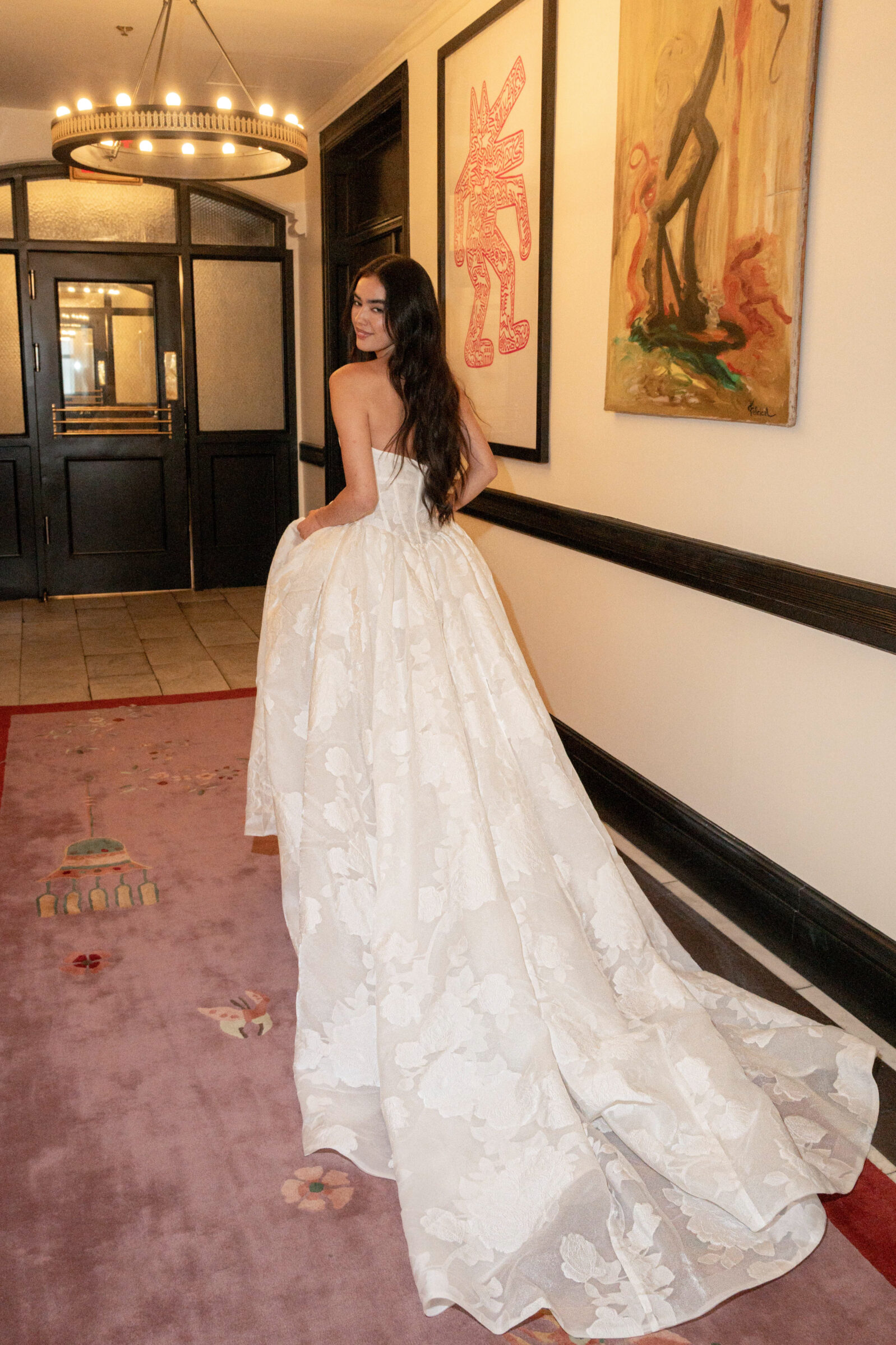 la premiere bride holding up her wedding dress train and running down a hallway.