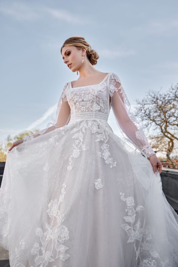 Stunning bride to be showing off her lace long sleeve wedding dress with a square neckline and roses embroidered throughout.