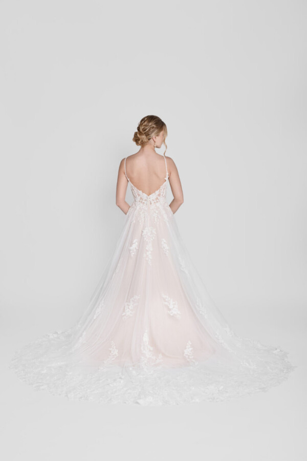 Shy bride wearing a spaghetti strap wedding dress with a deep v cut back and floral detailing on the bodice that flows down onto the flowy, tulle skirt.