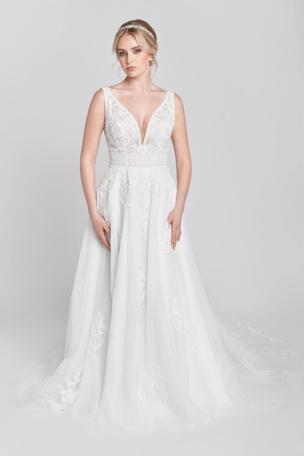 Bride to be wearing her lace wedding dress with a deep v cut neckline and floral lace detailing on the bodice. The skirt has lace detailing around the train.