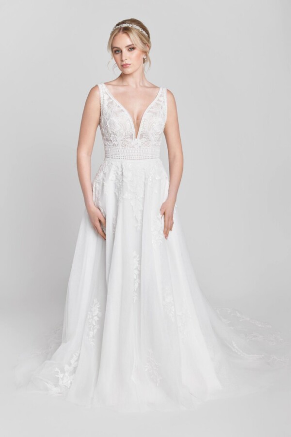 Bride to be wearing her lace wedding dress with a deep v cut neckline and floral lace detailing on the bodice. The skirt has lace detailing around the train.