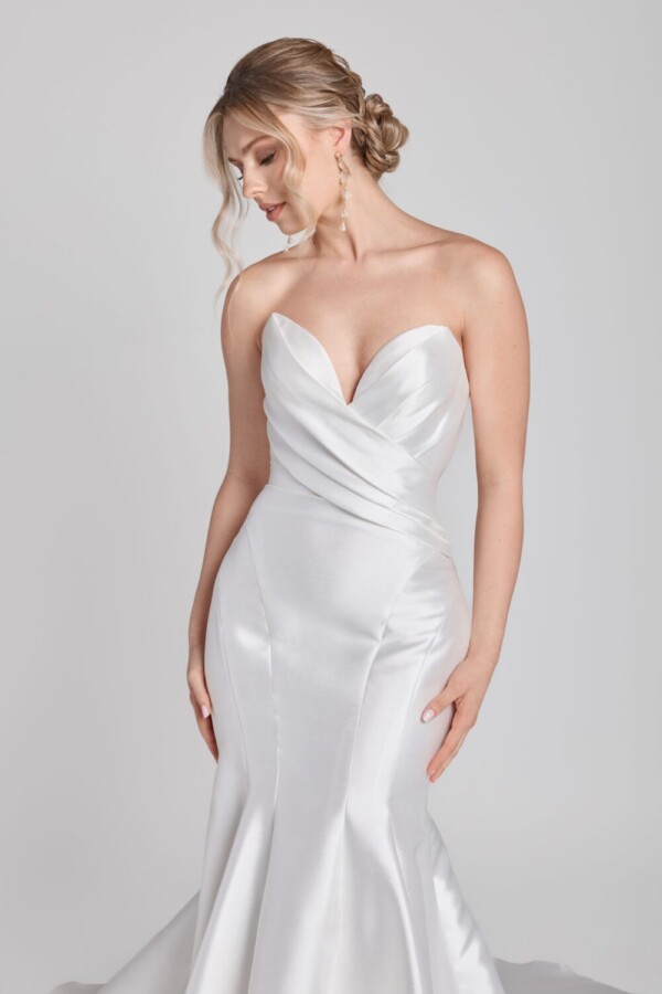Bride to be wearing a simple fit and flare wedding dress with a deep sweetheart neckline and crossover folding on bodice.