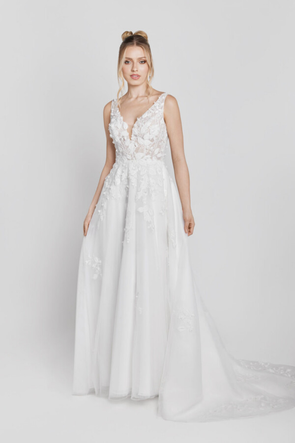 A charming floral wedding gown with lace decals on the bodice that flow onto the skirt worn by a sweet, young bride to be.