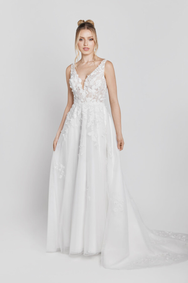 A charming floral wedding gown with lace decals on the bodice that flow onto the skirt worn by a sweet, young bride to be.