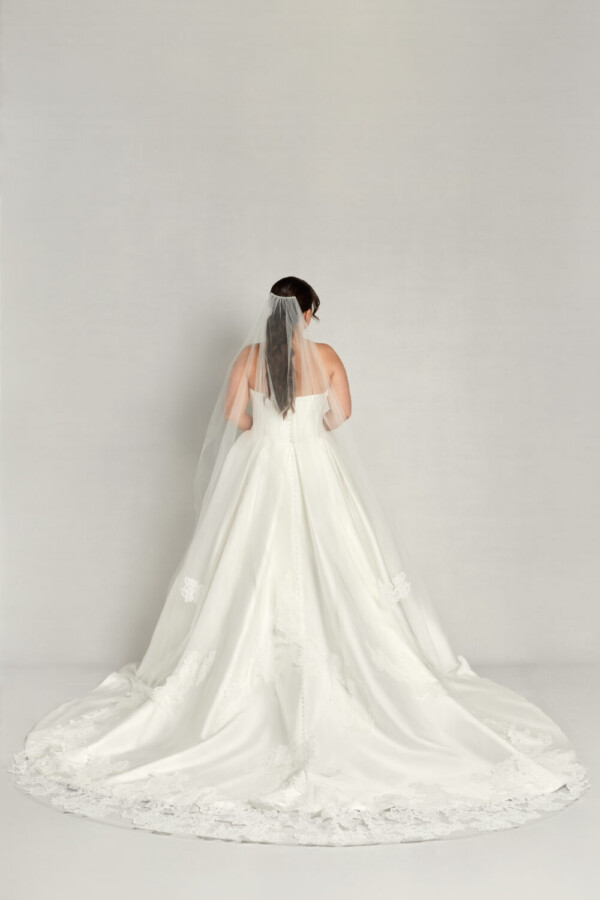 Stunning classic, basque waist wedding dress where the skirt is spread in a circle and the bride is wearing a complimentary long veil.