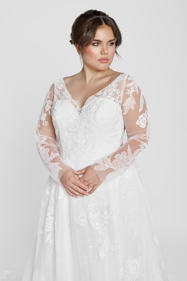 Plus size bride wearing a modest wedding dress with long lace sleeves.