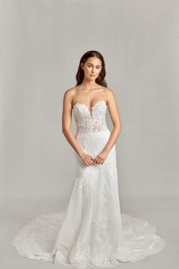 Sleeveless, sweetheard neckline wedding dress with floral decals on the bodice and onto the skirt pooling at the bride to be's feet.