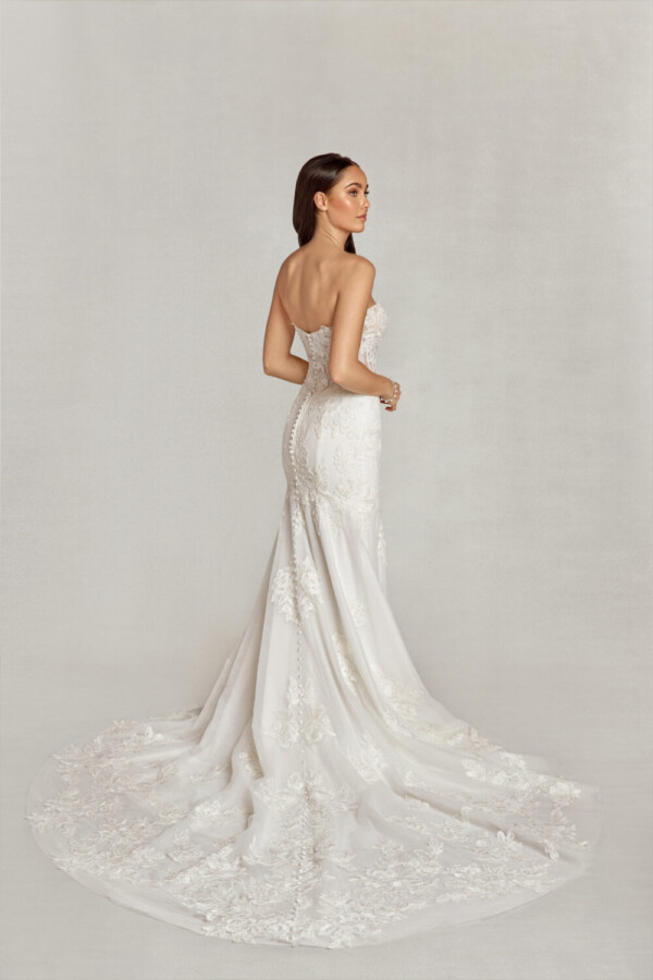 Sleeveless, sweetheard neckline wedding dress with floral decals on the bodice and onto the skirt pooling at the bride to be's feet.