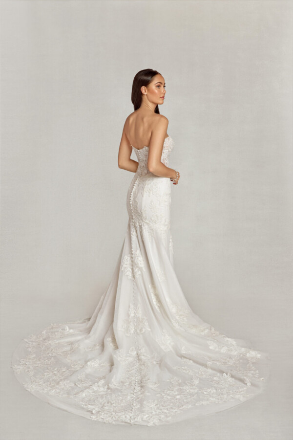 Sleeveless, sweetheard neckline wedding dress with floral decals on the bodice and onto the skirt pooling at the bride to be's feet.