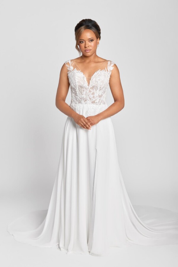 Model wearing a floral lace wedding dress with a see through lace bodice and a simple skirt spread around her.