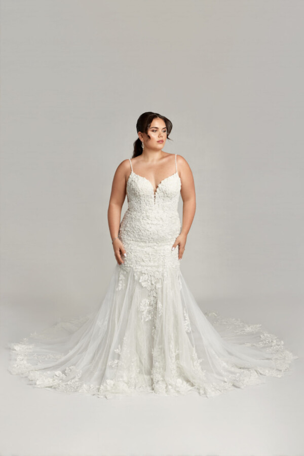 Gorgeous plus size bride wearing a bohemian wedding dress with spaghetti straps and floral detailing throughout.