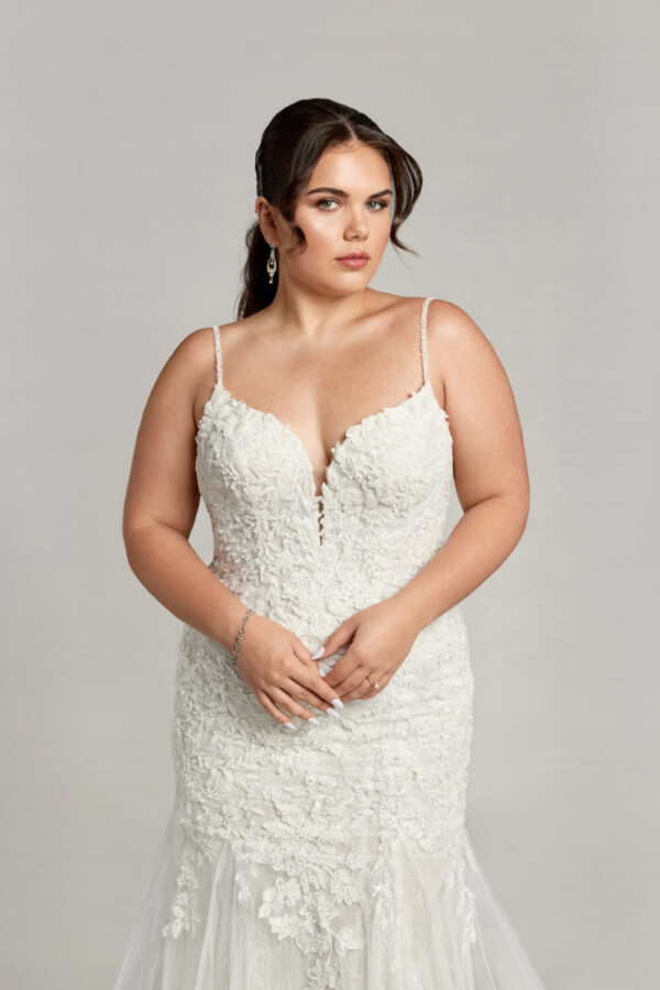Gorgeous plus size bride wearing a bohemian wedding dress with spaghetti straps and floral detailing throughout.
