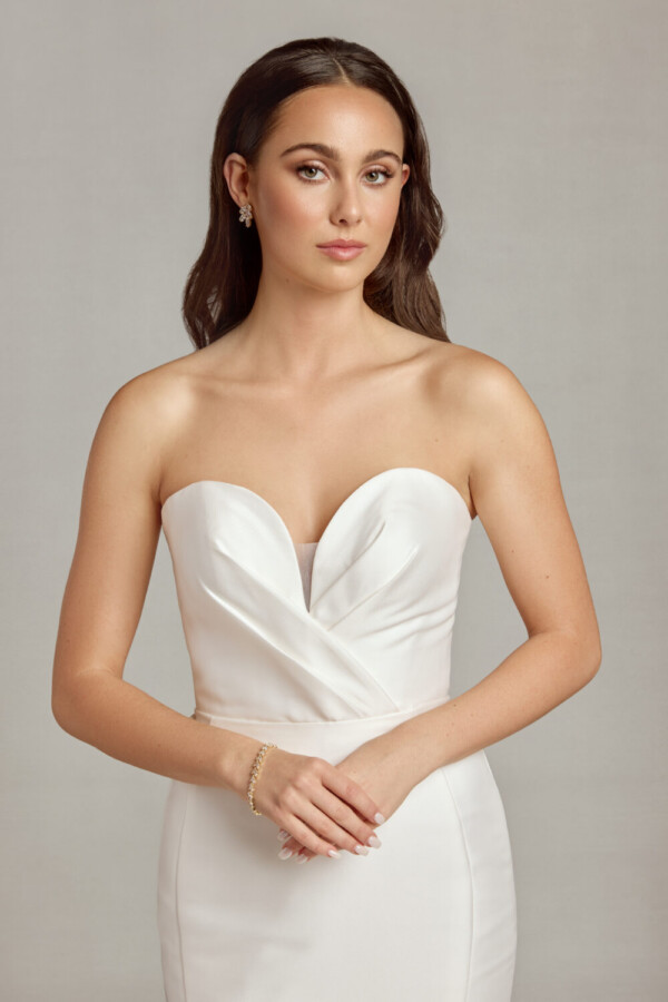Bride wearing her classic, form fitting wedding dress with deep sweetheart neckline and crossover folding on the bodice.