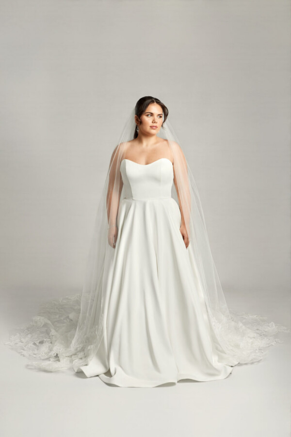 Timeless bride to be wearing a simple wedding dress with a sweetheart neckline and basque waistline.