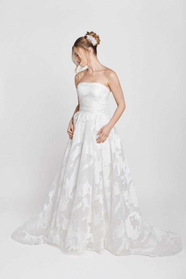 Strapless wedding dress with patterned fabric on the skirt being worn by a shy bride to be.