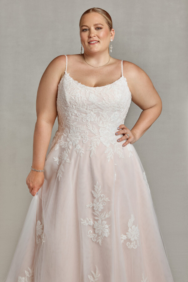 Beautiful bride wearing a blush wedding dress with spaghetti straps and floral decals on the bodice.