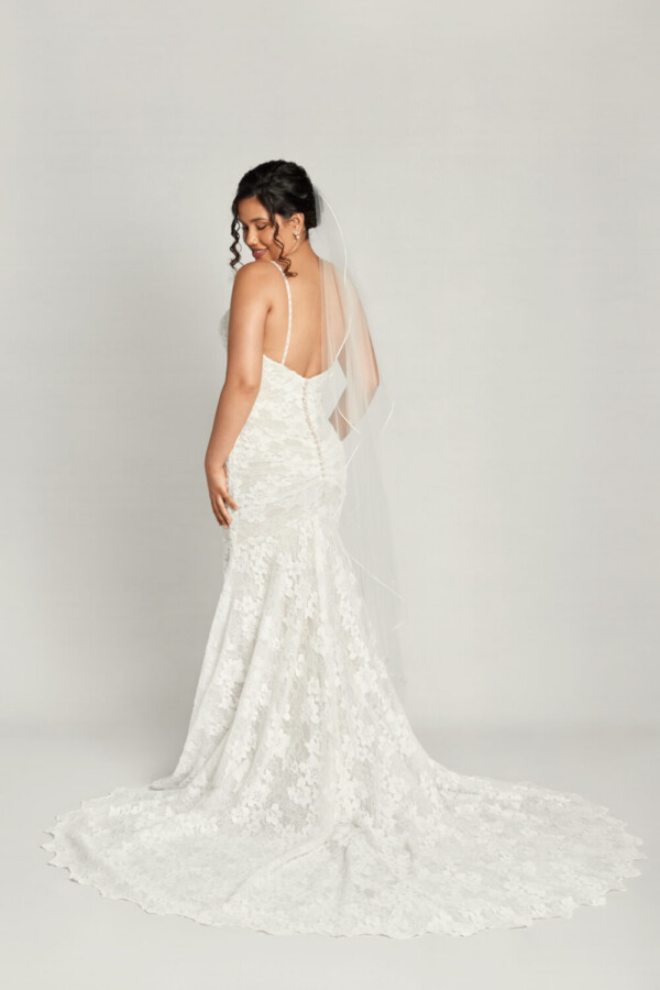 Traditional boho lace wedding dress with spaghetti straps and floral lace overlay and buttons down the back.