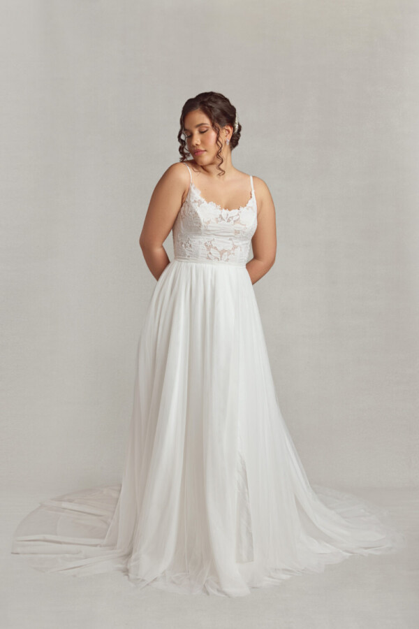 Stunning wedding dress with lace bodice and a flowing, layered skirt worn by a shy bride to be.