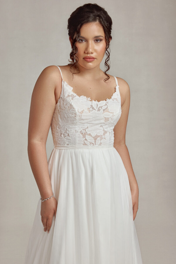 Bride to be wearing a stunning wedding dress with lace bodice and a flowing, layered skirt.