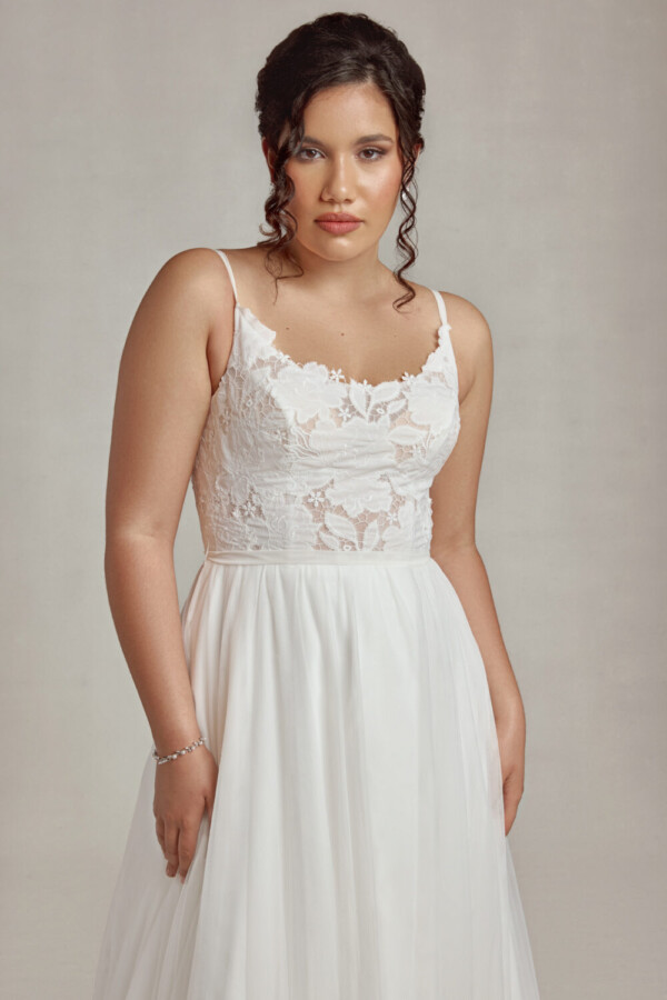 Bride to be wearing a stunning wedding dress with lace bodice and a flowing, layered skirt.