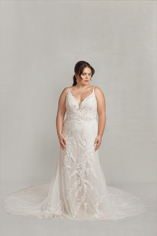 Bride to be wearing a boho wedding dress with spaghetti straps and floral lace appliques throughout.