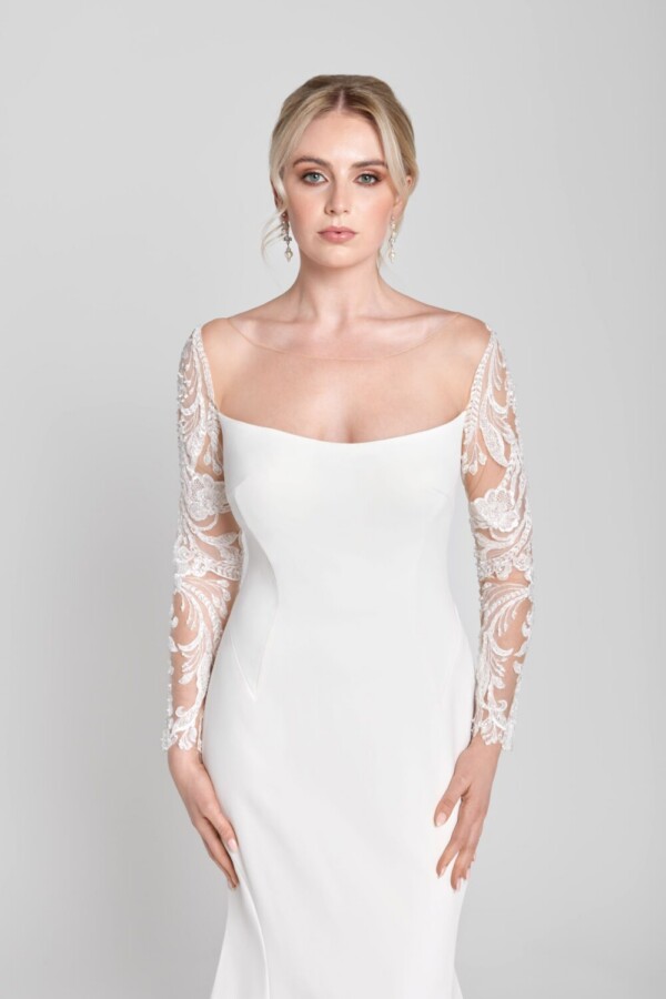 Stunning bride to be wearing a simple, sheath wedding dress with lace, long sleeves.