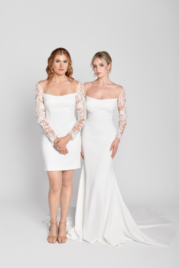 Stunning brides standing together wearing the same simple, sheath wedding dress with lace, long sleeves, one dress short and one long.