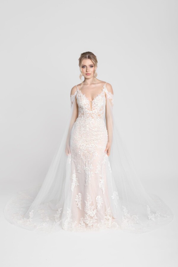 Stunning lace wedding dress with a long flowing cape worn by a confident bride to be.