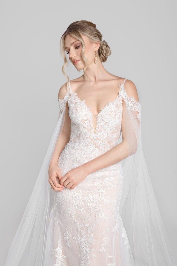 Stunning lace wedding dress with a long flowing cape worn by a confident bride to be.