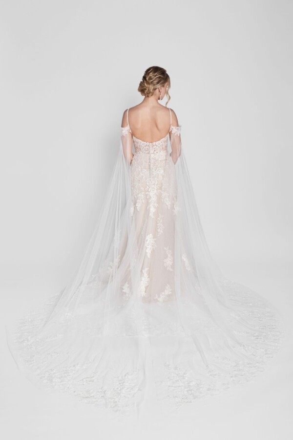 Stunning lace wedding dress with a long flowing cape worn by a confident bride to be.