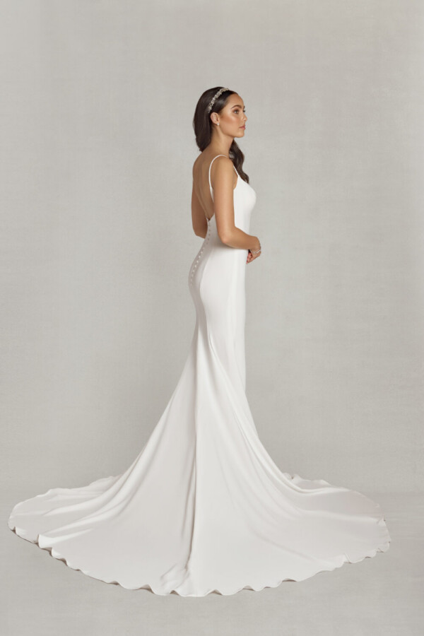 Simple sheath wedding dress with a square neckline and spaghetti straps being worn by a confident bride to be.