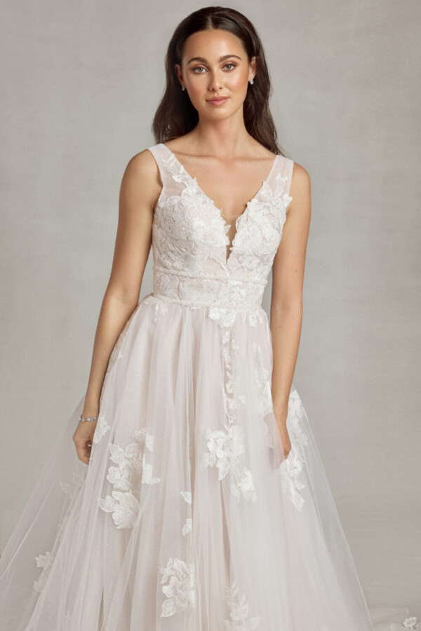 Whimsical bride to be wearing a bohemian wedding dress with floral lace on the bodice and a multilayered, tulle skirt.