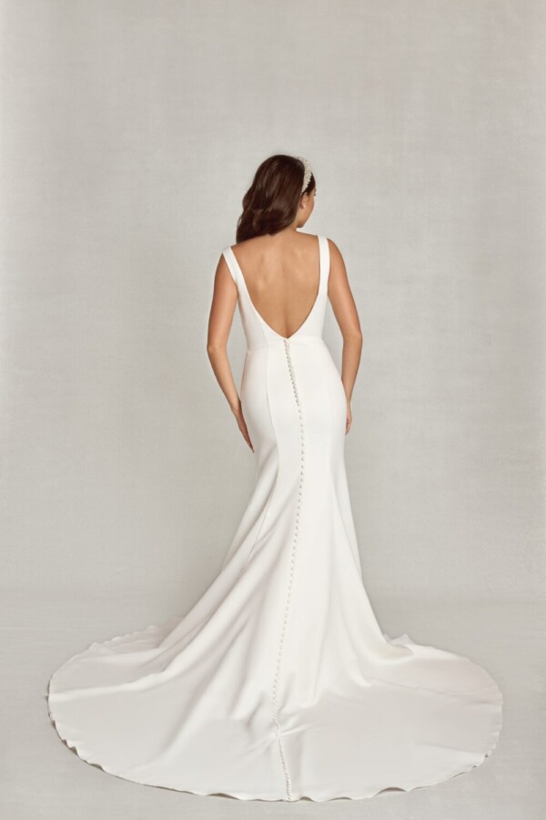 Simple bride to be wearing a traditional, fit and flare wedding dress with a deep back and buttons down the back.
