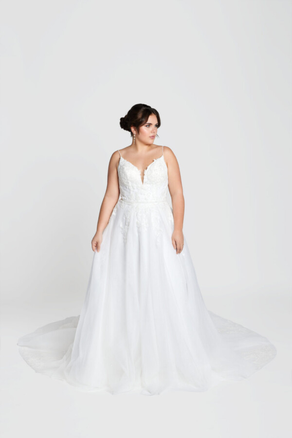 Classic bride to be modeling a traditional style wedding dress with spaghetti straps and lace decals on the bodice.