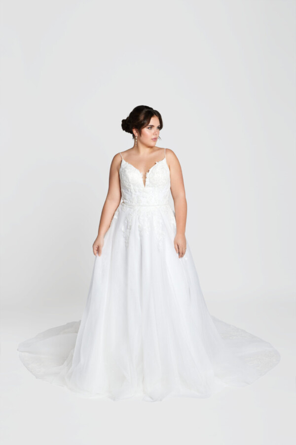 Classic bride to be modeling a traditional style wedding dress with spaghetti straps and lace decals on the bodice.