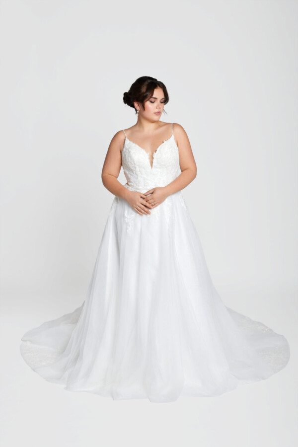 Classic bride to be modeling a traditional style wedding dress with spaghetti straps and lace decals on the bodice.