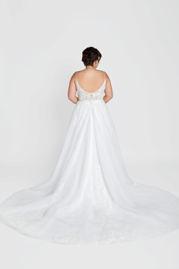 Classic bride to be modeling a traditional style wedding dress with spaghetti straps and lace decals on the bodice.