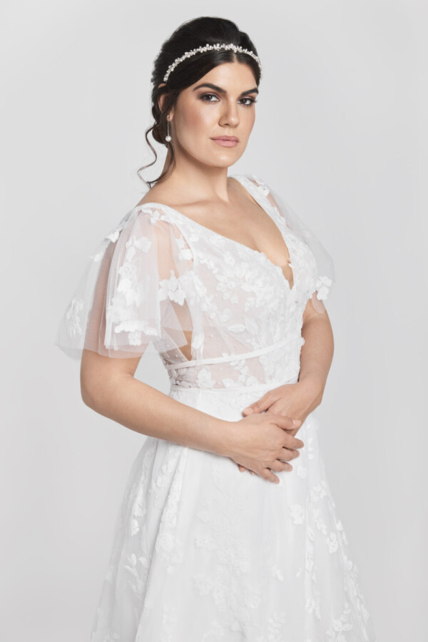 Gorgeous bride wearing a wedding dress with short sleeves and floral lace detailing on the bodice flowing into the multilayered tulle skirt.