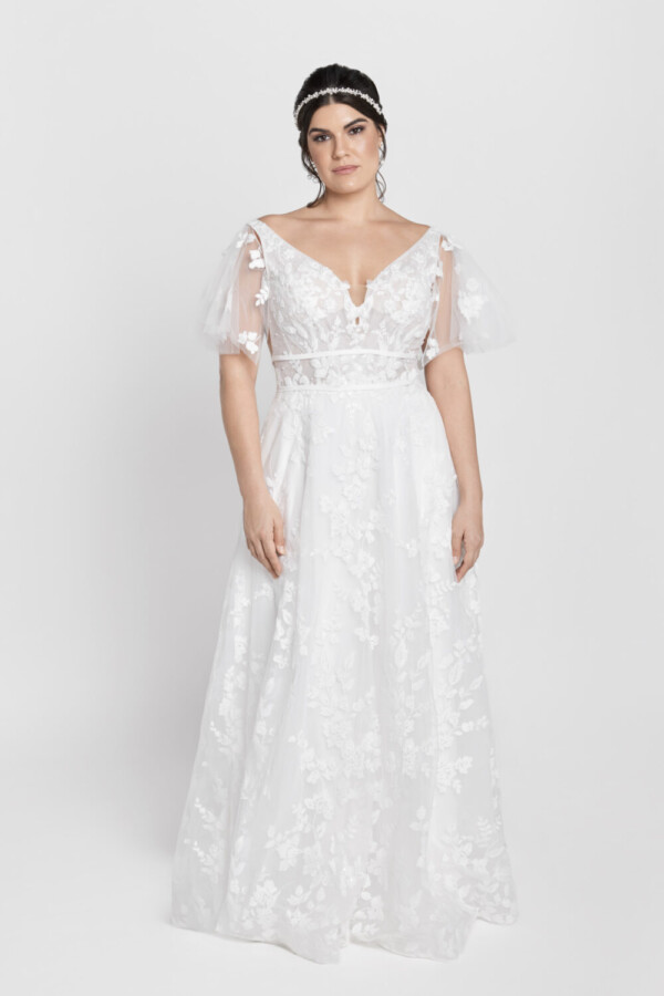 Gorgeous bride wearing a wedding dress with short sleeves and floral lace detailing on the bodice flowing into the multilayered tulle skirt.