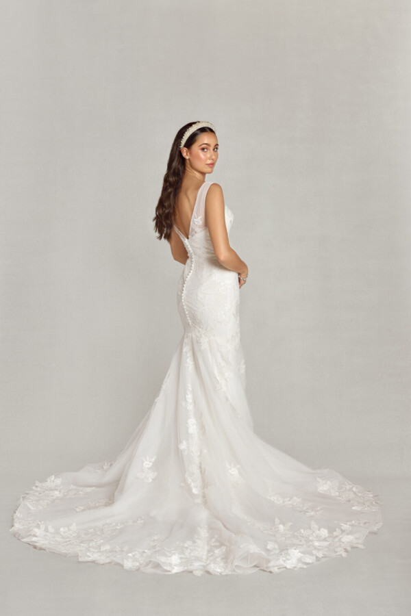 Young bride to be wearing a sit and flare wedding dress with floral lace details on the bodice flowing onto the multilayered, tulle skirt spread around her with a train.