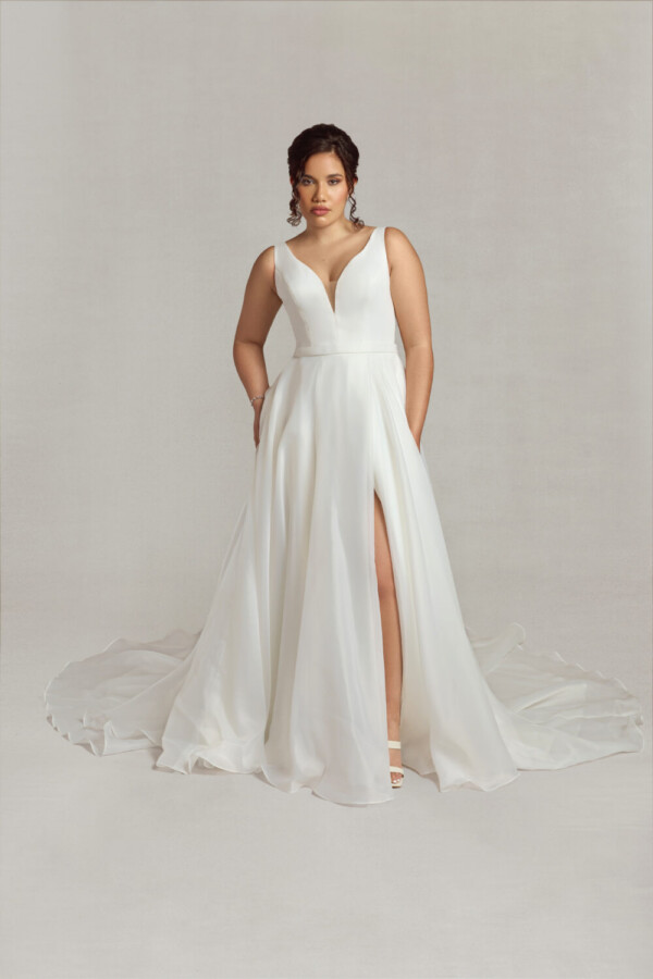Bride wearing a traditional style wedding dress with a deep v neck line, a slit in the skirt and hidden pockets.