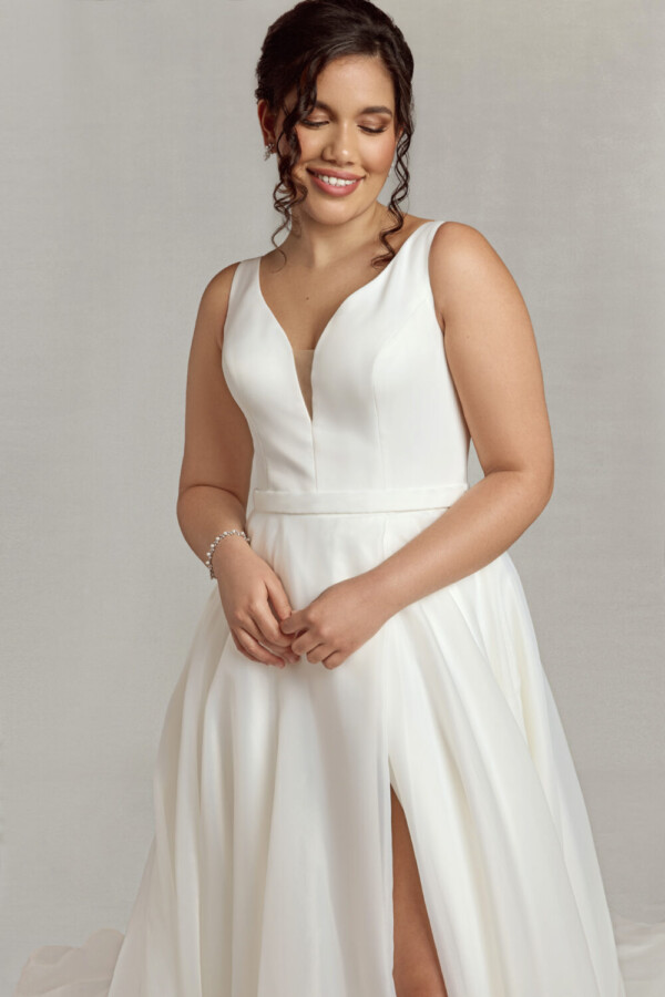 Bride wearing a traditional style wedding dress with a deep v neck line, a slit in the skirt and hidden pockets.