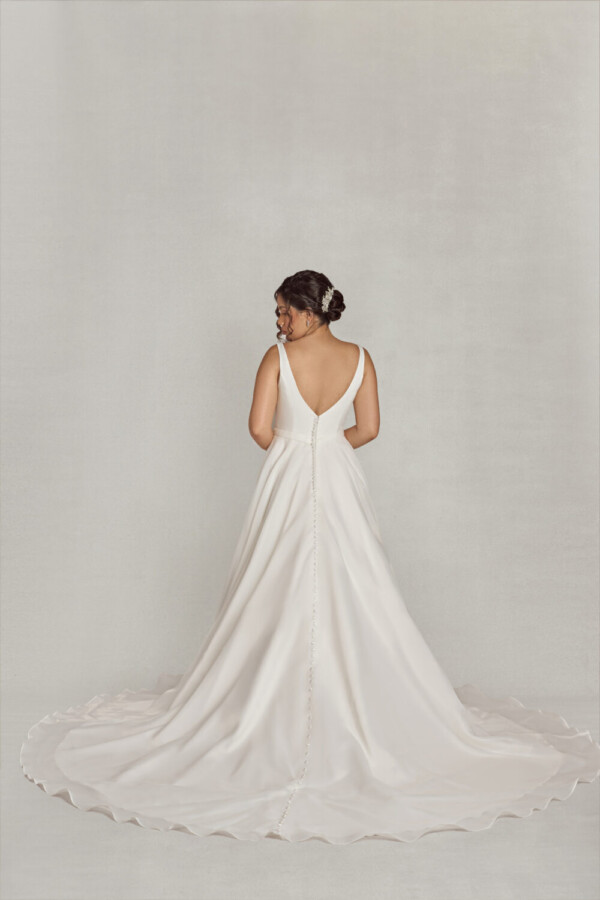 Bride wearing a traditional style wedding dress with a deep v neck line, a slit in the skirt and buttons down the back.