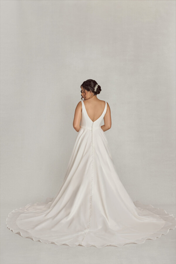 Bride wearing a traditional style wedding dress with a deep v neck line, a slit in the skirt and buttons down the back.