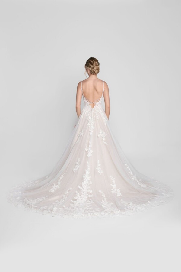 Charming bride to be wearing a spaghetti strap wedding dress with floral lace decals on the bodice and flowing onto the multilayered tulle skirt.