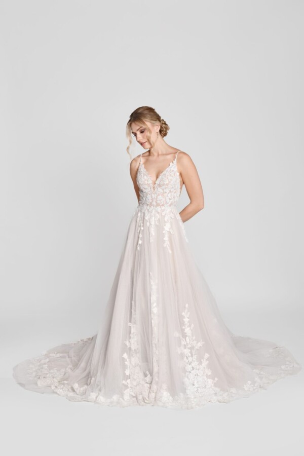 Charming bride to be wearing a spaghetti strap wedding dress with floral lace decals on the bodice and flowing onto the multilayered tulle skirt.